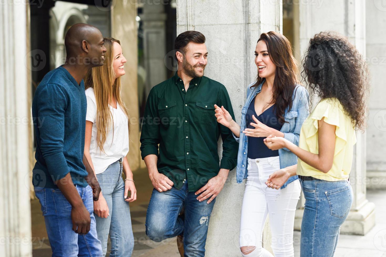 Grupo multiétnico de amigos divirtiéndose juntos en el fondo urbano foto