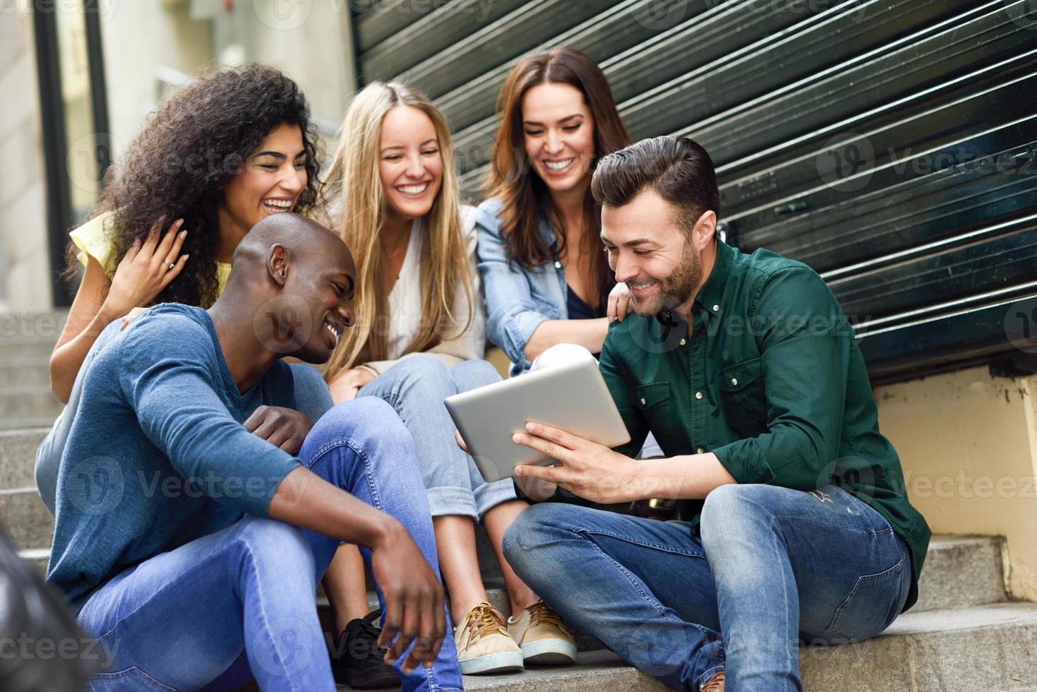 grupo multiétnico de jóvenes mirando una tableta foto