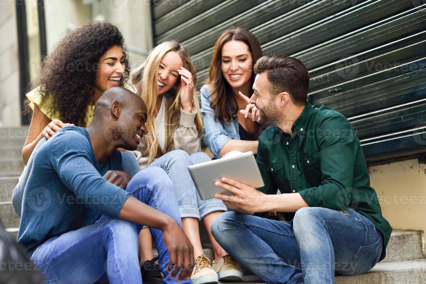 grupo multiétnico de jóvenes mirando una tableta foto