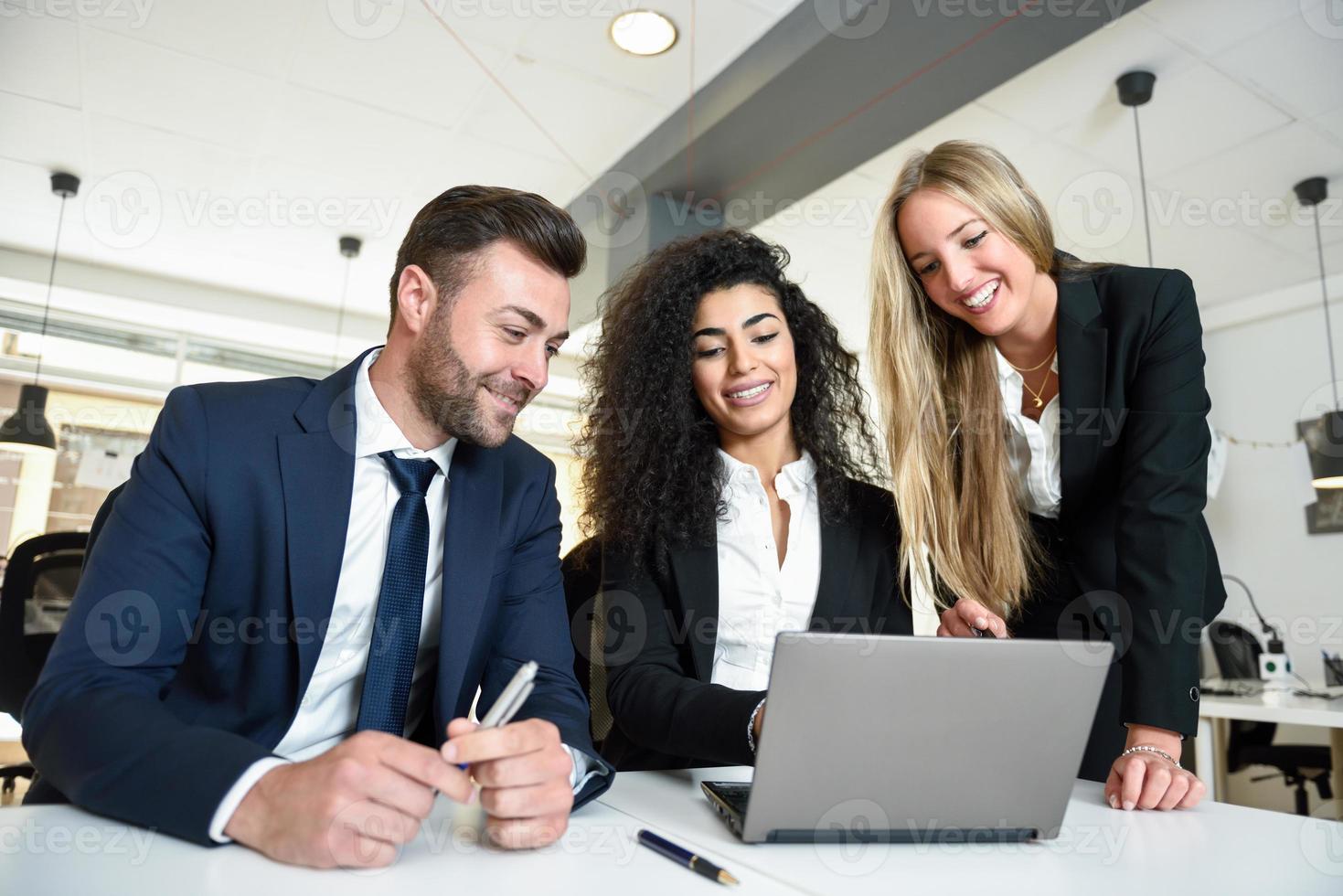 grupo multiétnico de tres empresarios reunidos en una oficina moderna. foto