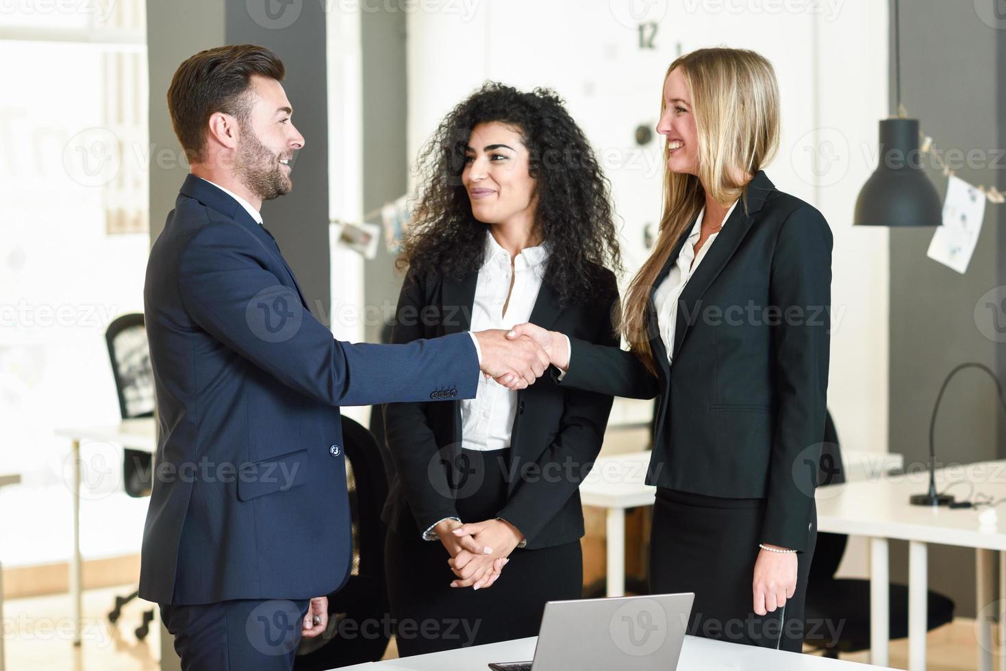 hombre y mujer caucásicos dándose la mano con traje. foto