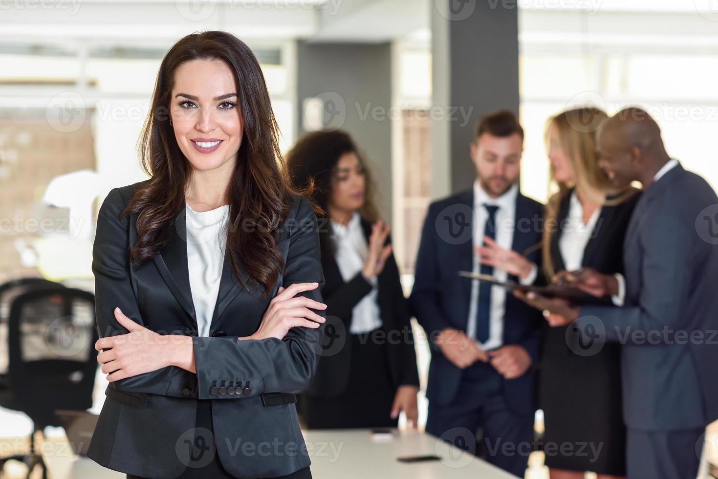 Líder empresaria en la oficina moderna con empresarios que trabajan en segundo plano. foto