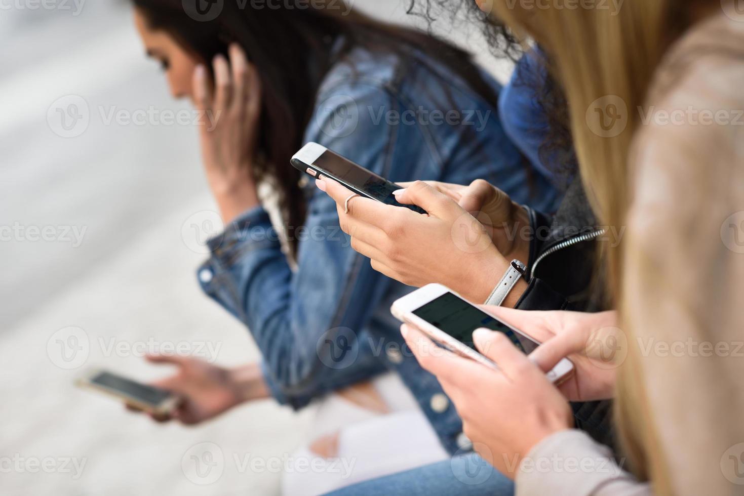 Jóvenes irreconocibles que usan teléfonos inteligentes y tabletas al aire libre foto