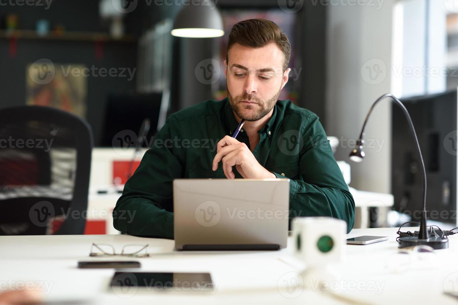 Young man studying with laptop computer on white desk. photo
