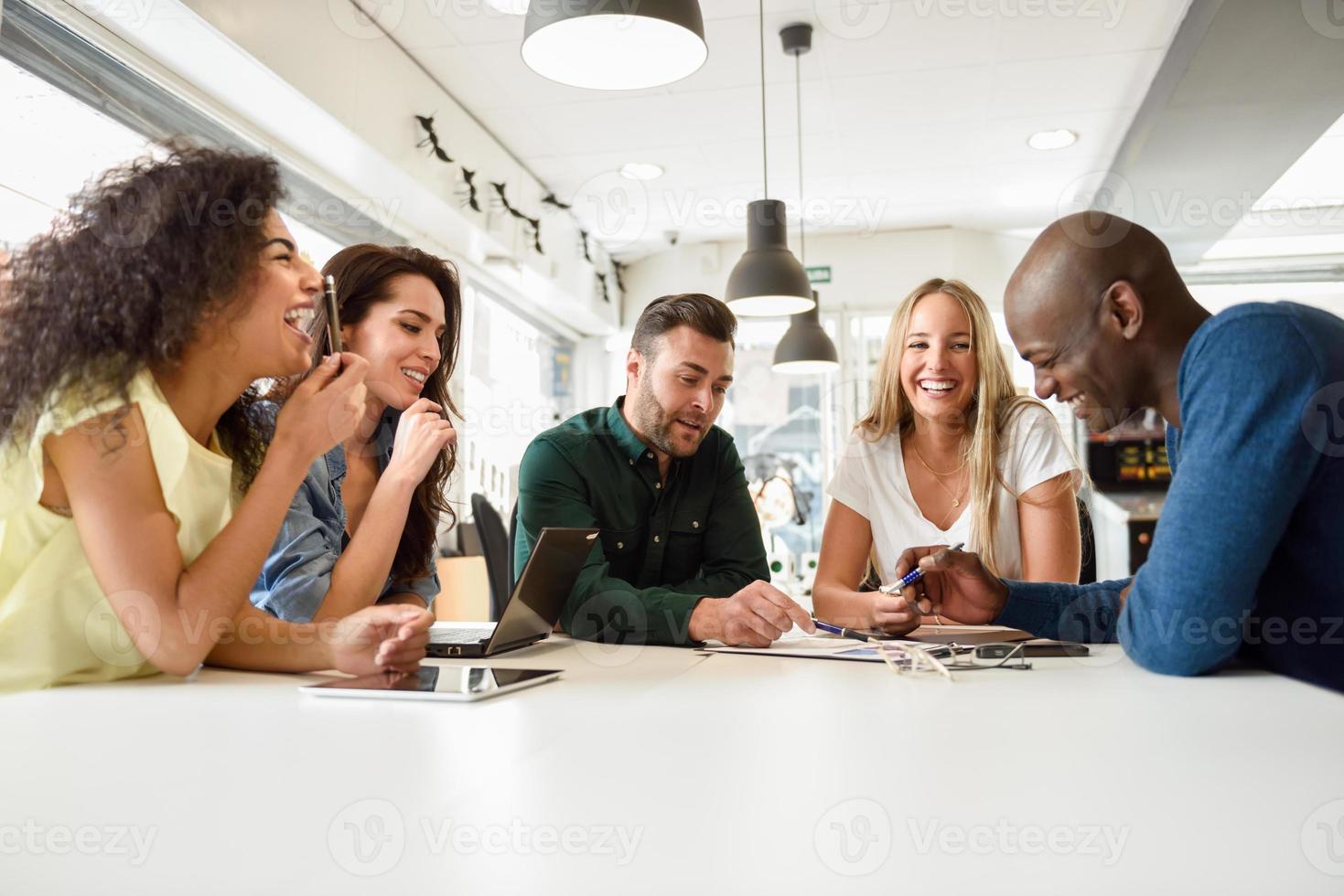 Grupo multiétnico de jóvenes que estudian juntos en el escritorio blanco foto