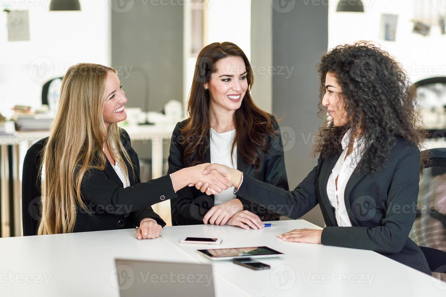 Three businesswomen shaking hands in a modern office photo