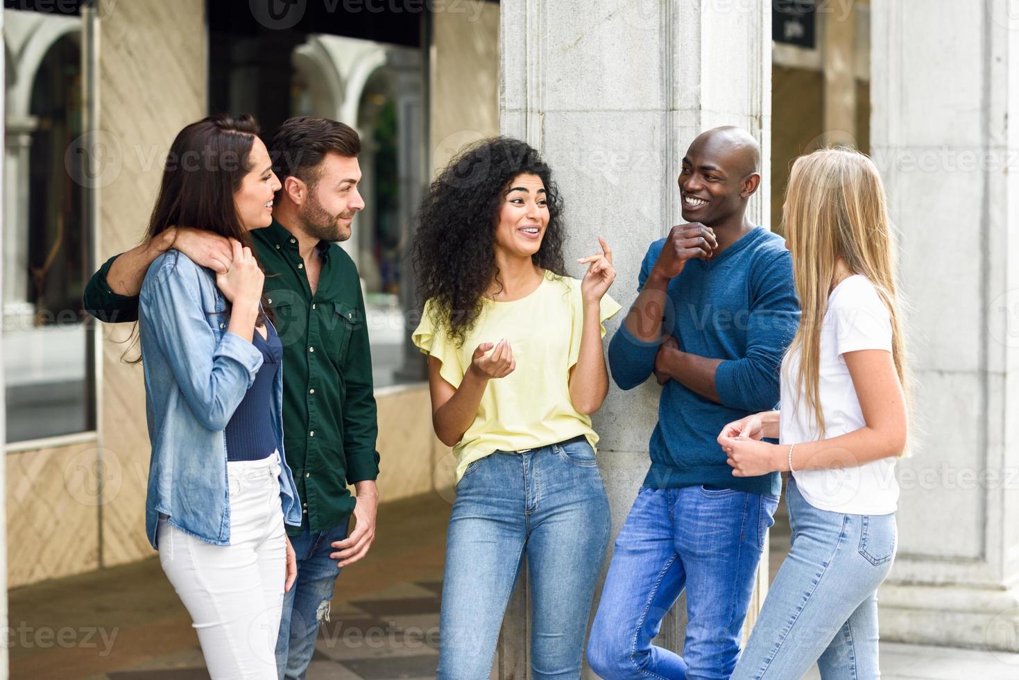 Grupo multiétnico de amigos divirtiéndose juntos en el fondo urbano foto