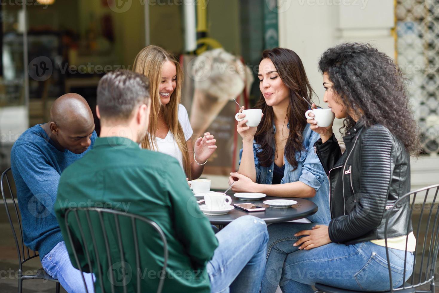 Multiracial group of five friends having a coffee together photo