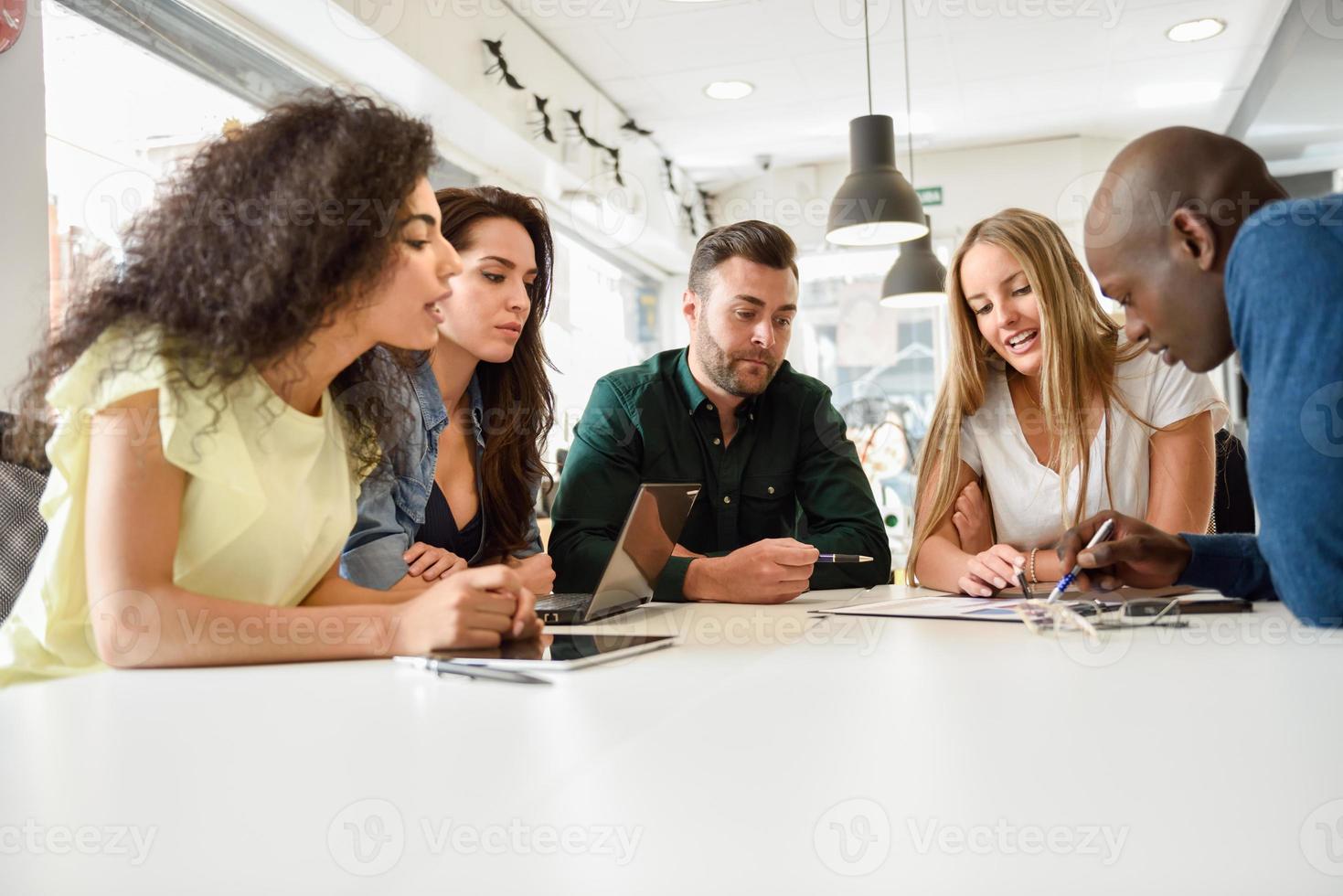 Grupo multiétnico de jóvenes que estudian juntos en el escritorio blanco foto