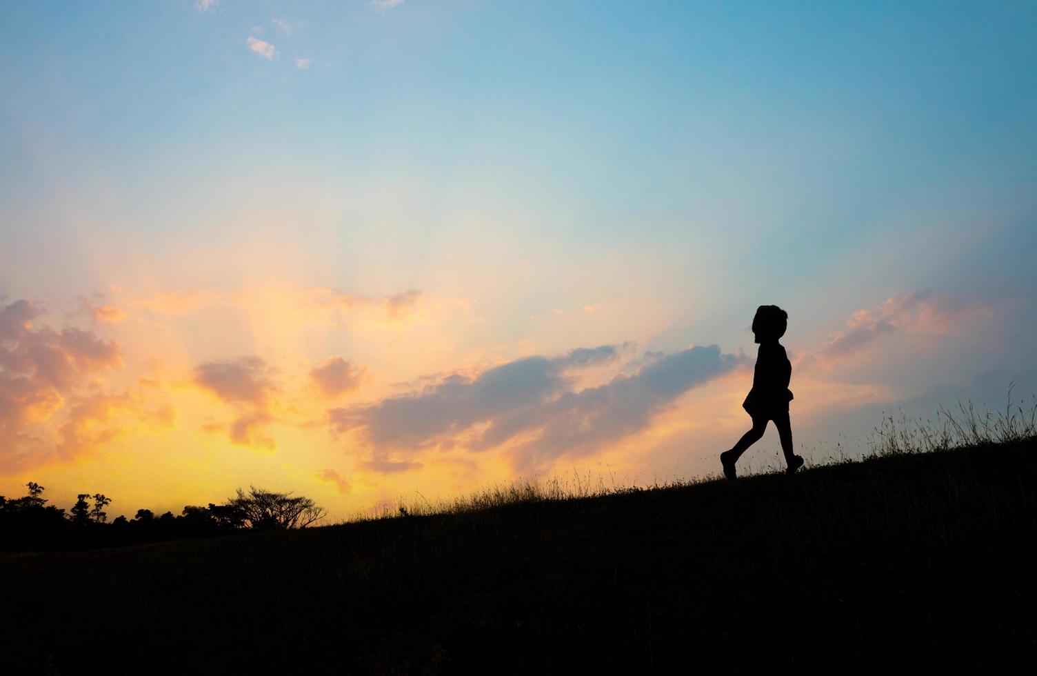 The silhouette of a girl running on the hill at sunset photo