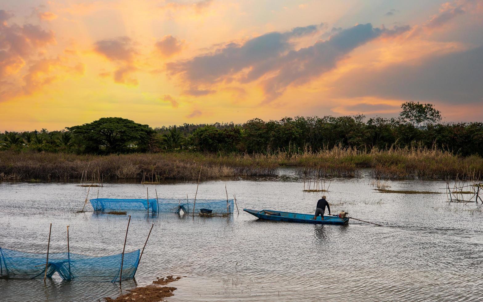 Rural wetlands and fishermen driving boats at sunset photo
