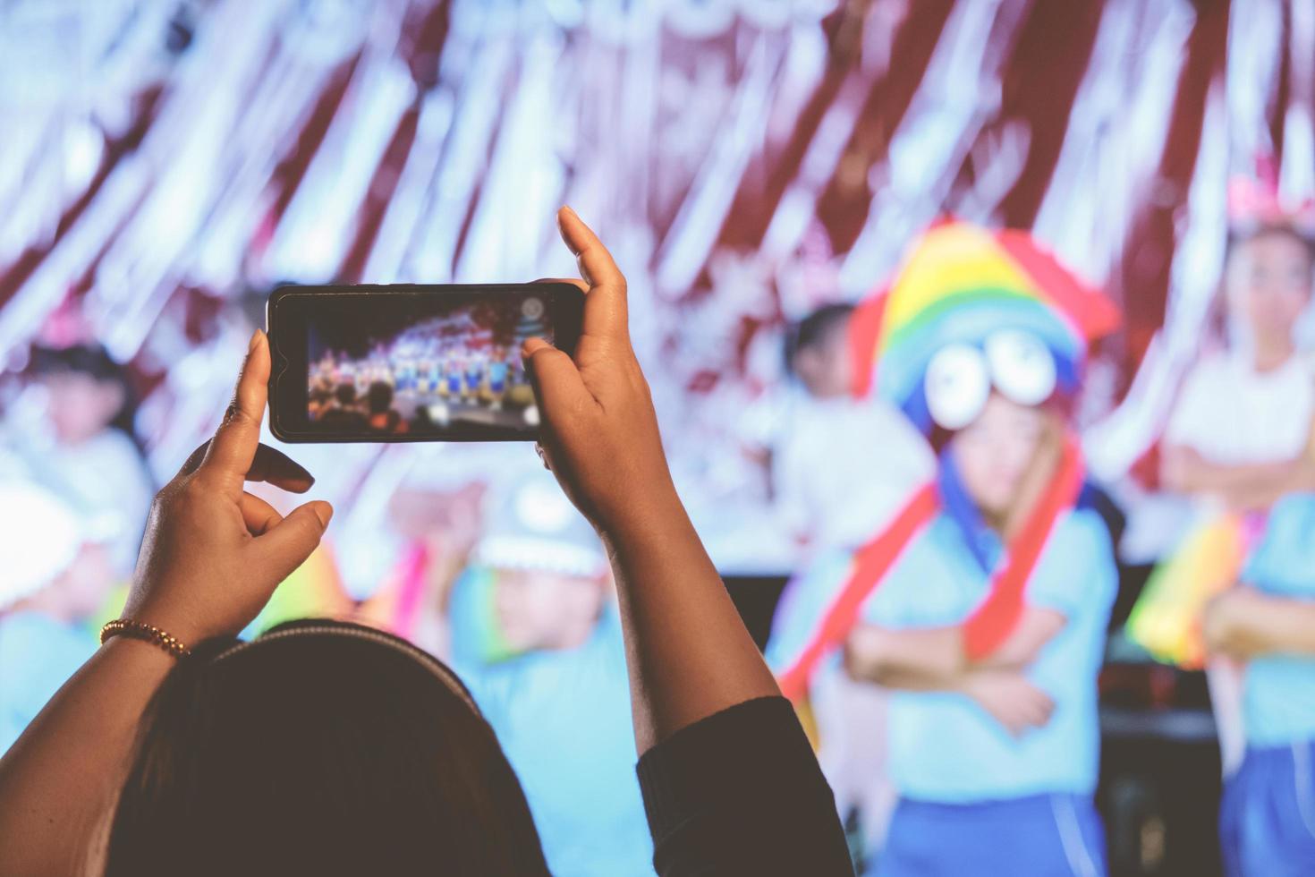 Parents use their phones to take pictures of their children on stage at school. photo