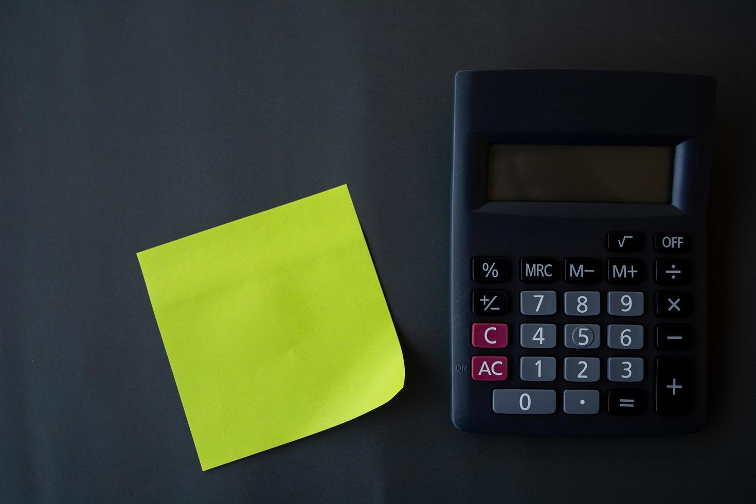 concepto de finanzas, papel recordatorio y calculadora sobre fondo negro foto
