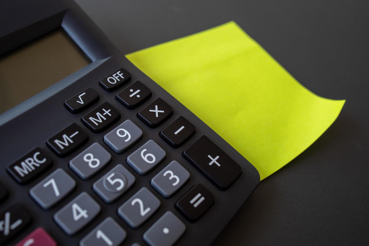 Finance concept, reminder paper and calculator on black background. photo