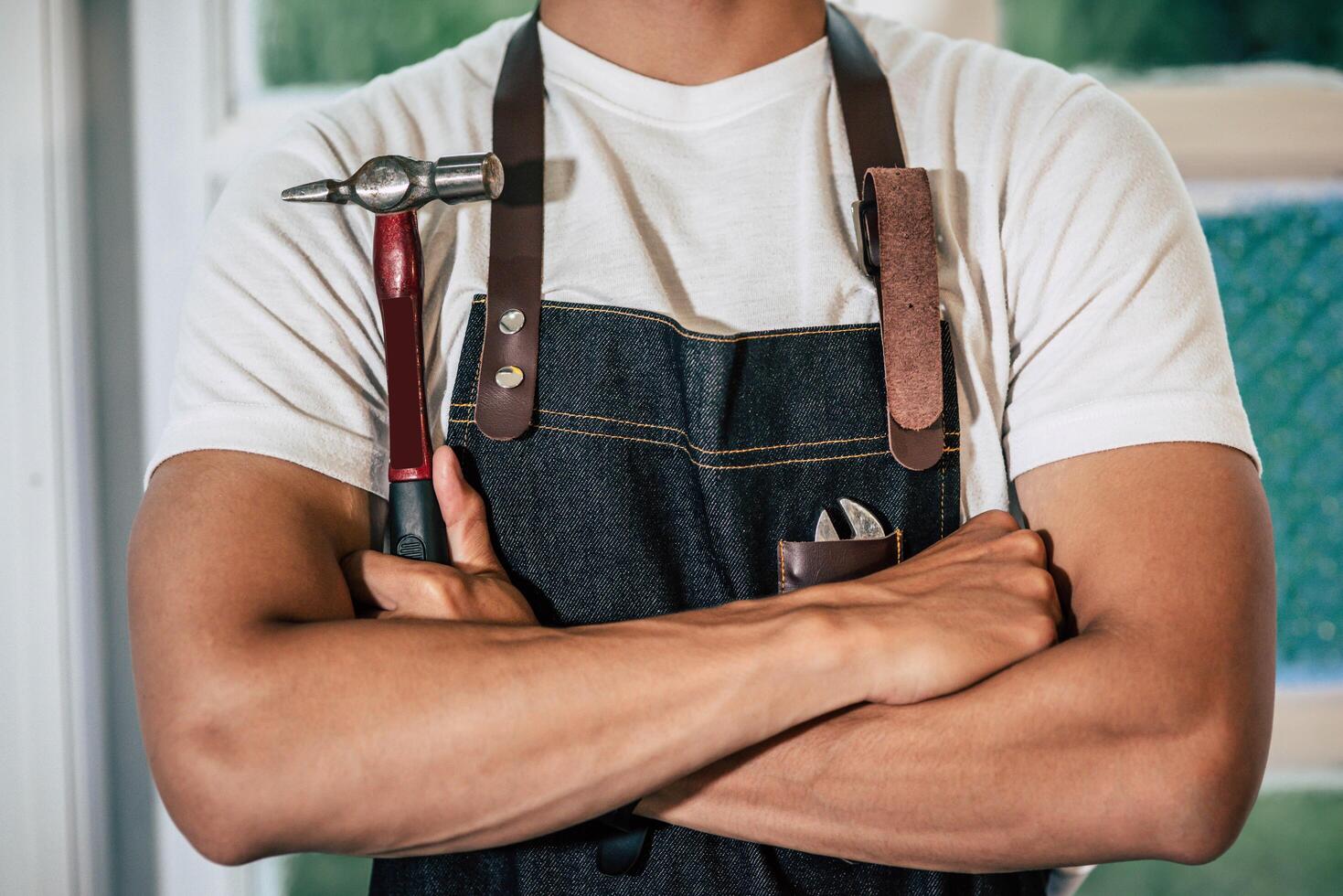 The carpenter stands and holds a hammer. photo