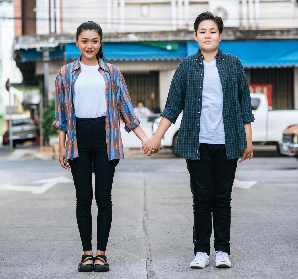 Two loving women standing and holding hands on the street. photo