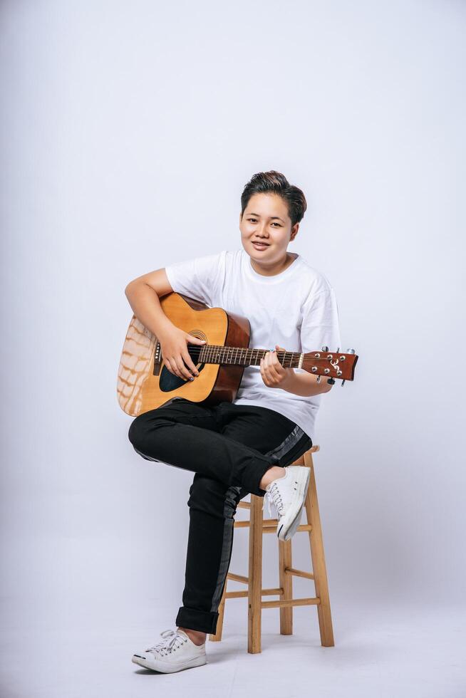 Girl sitting on a chair and playing guitar. photo