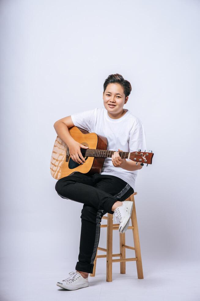 niña sentada en una silla y tocando la guitarra. foto