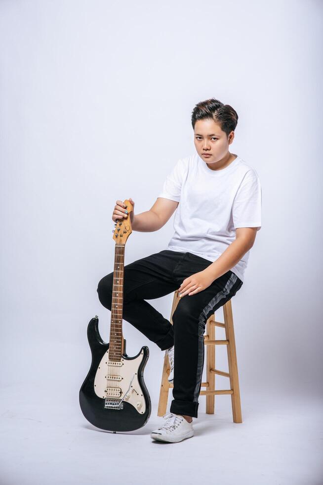 niña sentada en una silla y sosteniendo una guitarra. foto