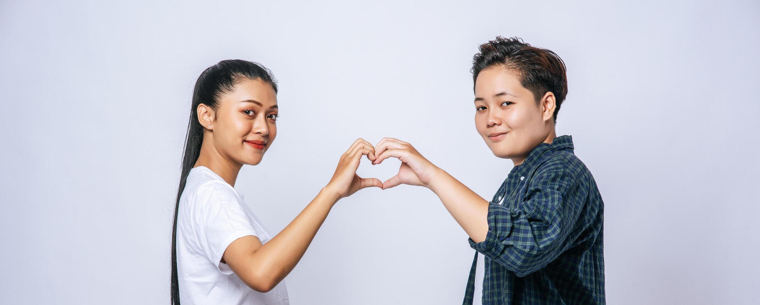 Two young women love each other hand mark heart shape. photo