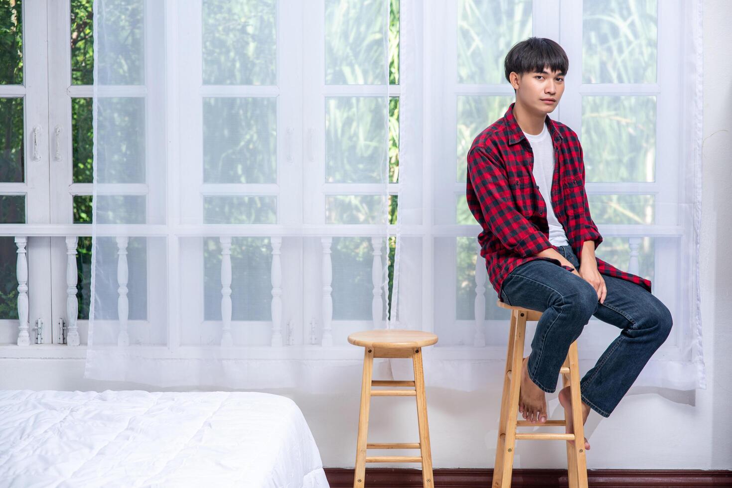 un joven con una camisa a rayas está sentado en una silla alta. foto