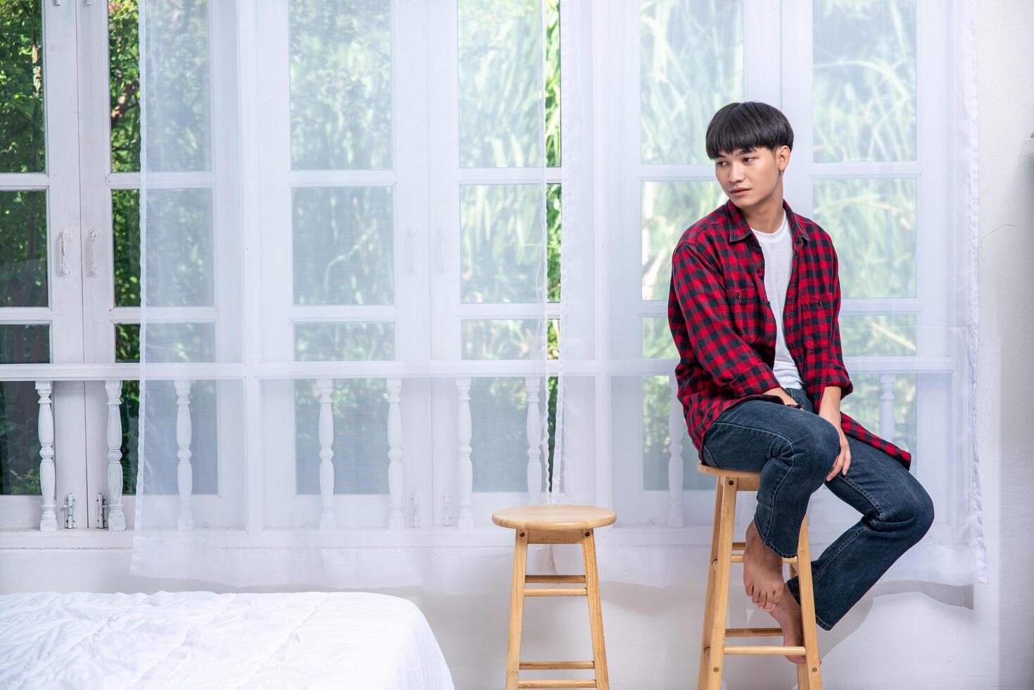 A young man in a striped shirt is sitting on a high chair. photo