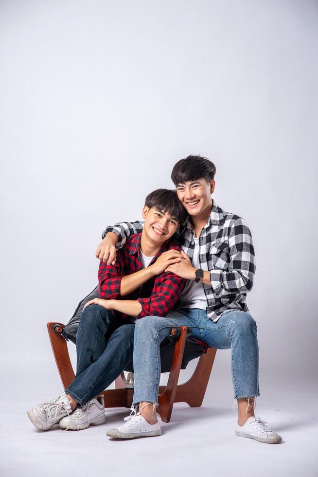 Two men who love each other hug and sit on a chair. photo