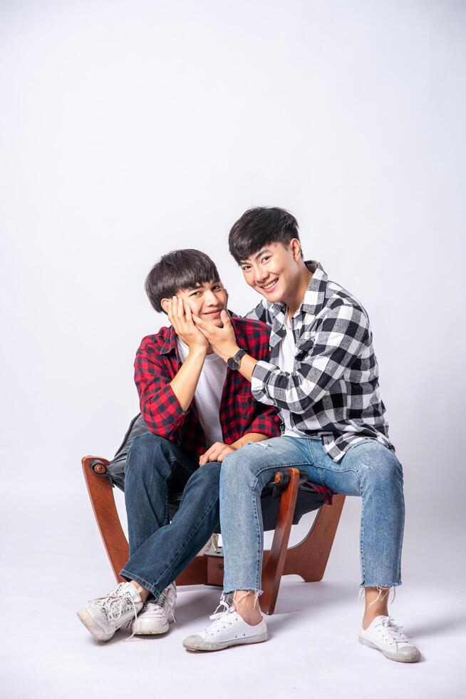 Two men who love each other hug and sit on a chair. photo