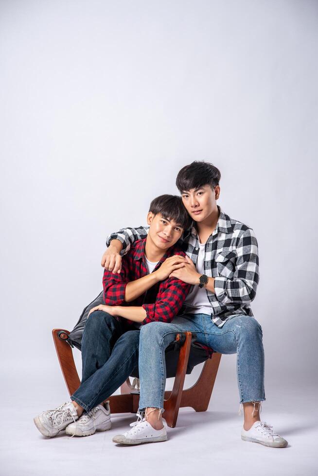 Two men who love each other hug and sit on a chair. photo