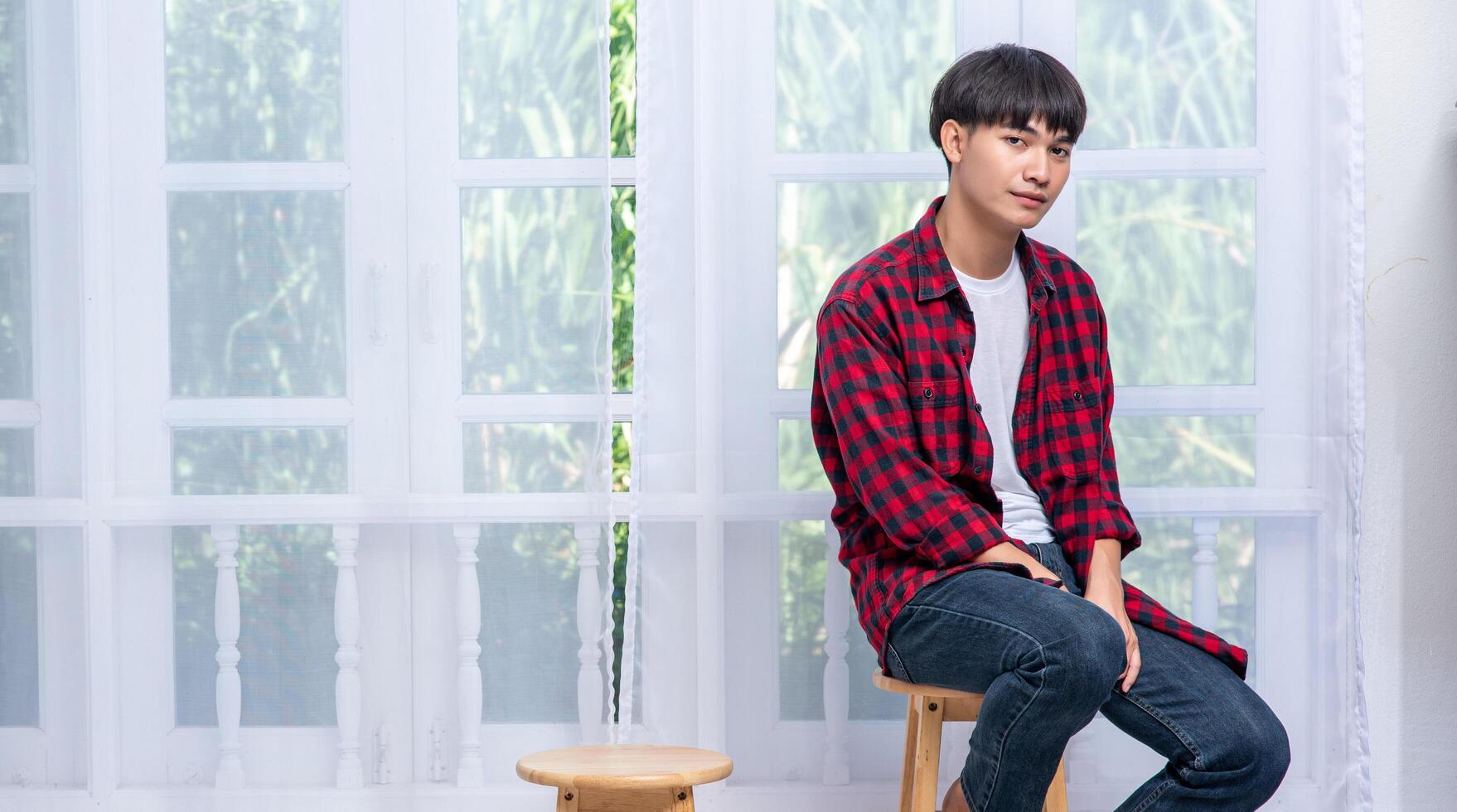 A young man in a striped shirt is sitting on a high chair. photo