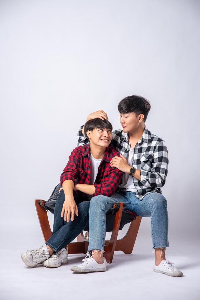 Two men who love each other hug and sit on a chair. photo