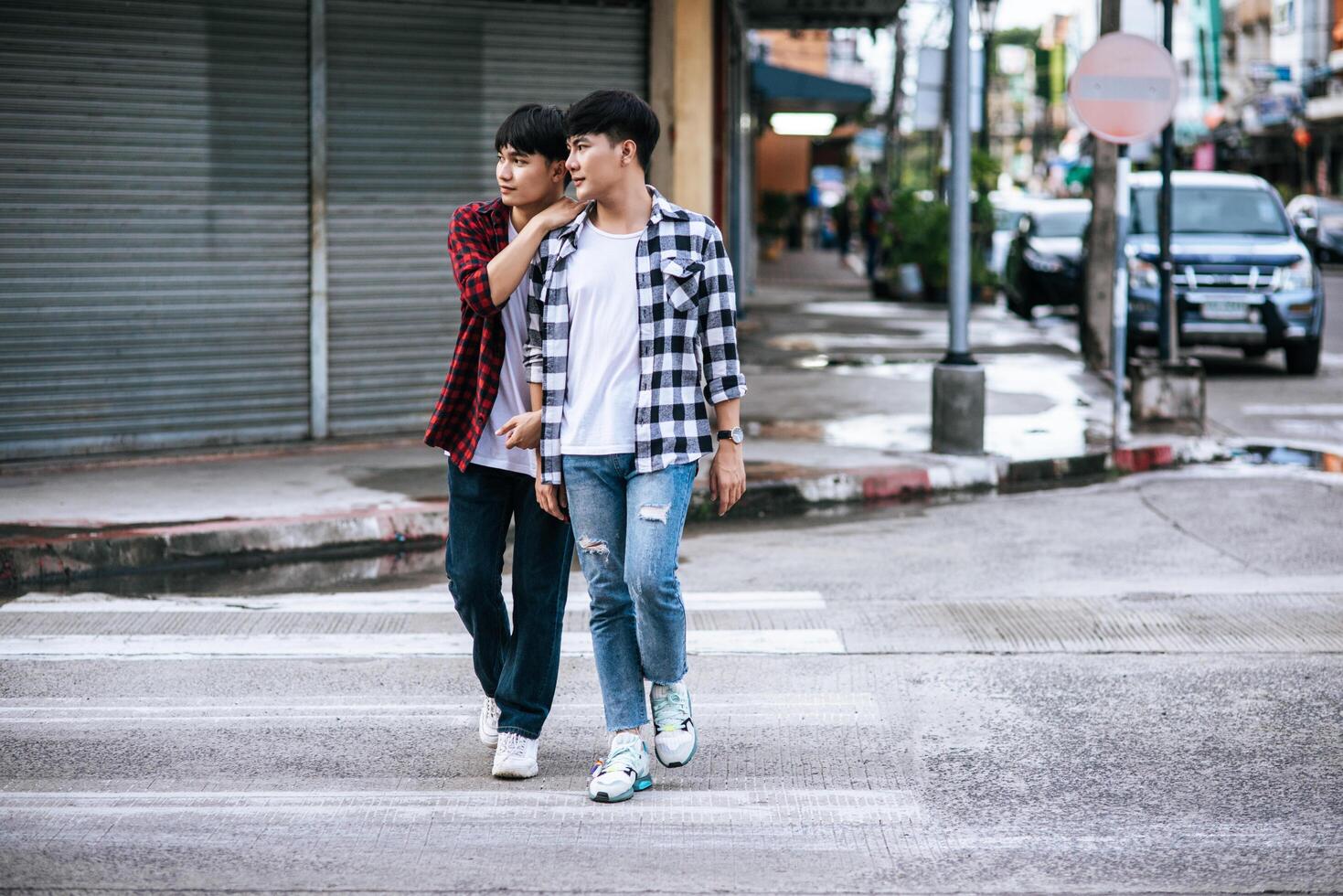 Two loving young men in shirts and walking on the street. photo