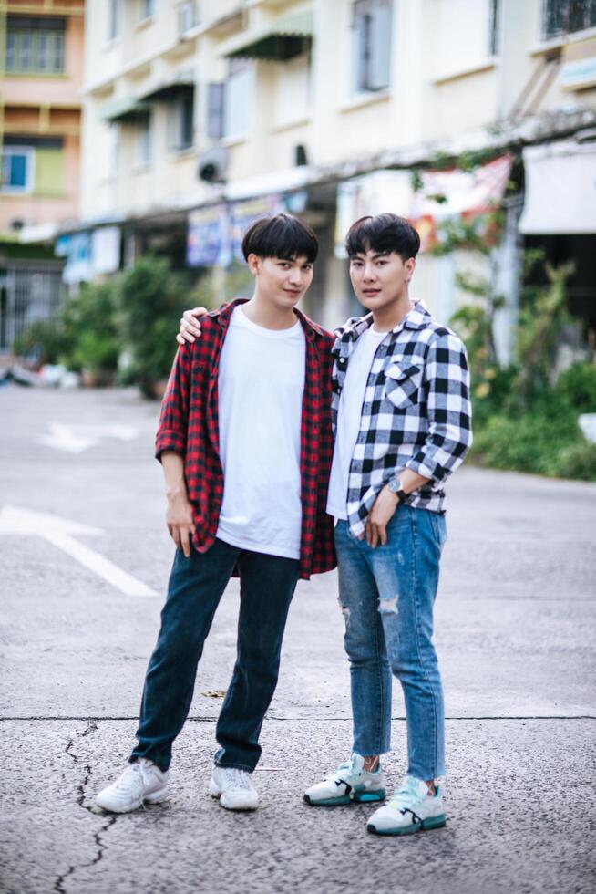 Two loving young men in shirts and standing on the street. photo
