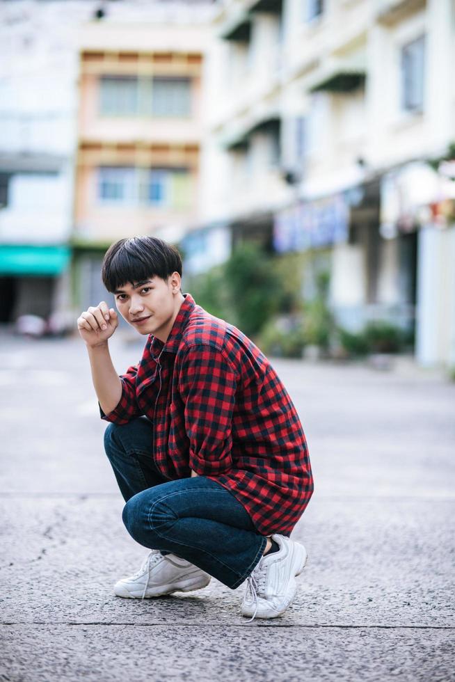 A young man in a striped shirt sitting on the street photo