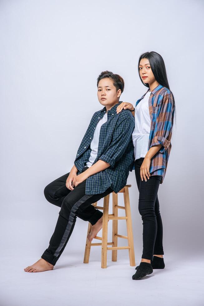 Two women lovers grab another shoulder and sit in a chair. photo