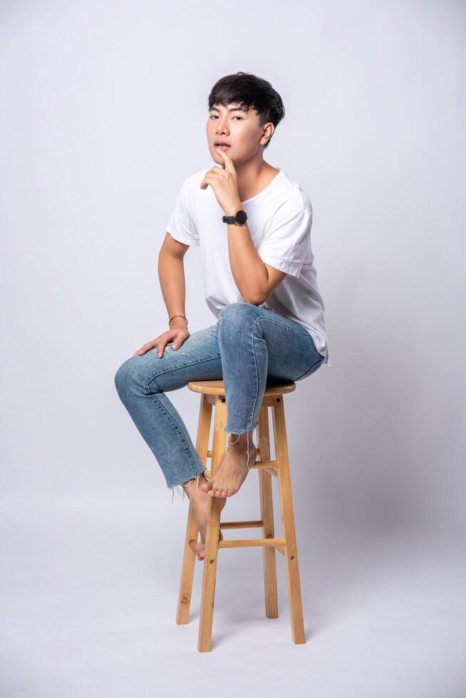A young man in a white T-shirt is sitting on a high chair. photo
