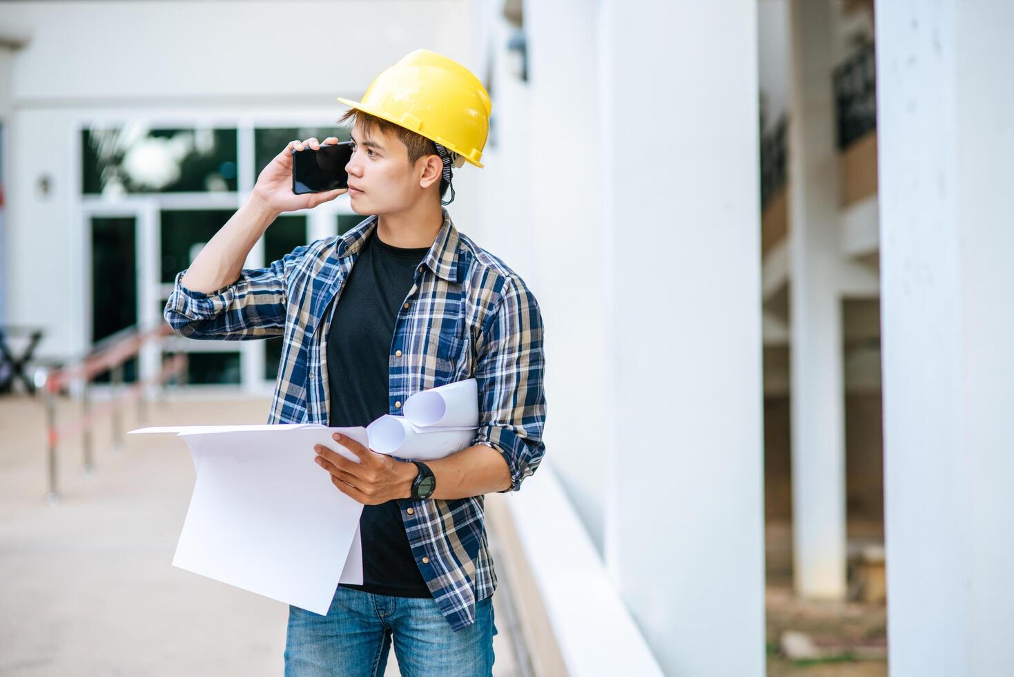 Architects hold floor plans and talk on the phone. photo