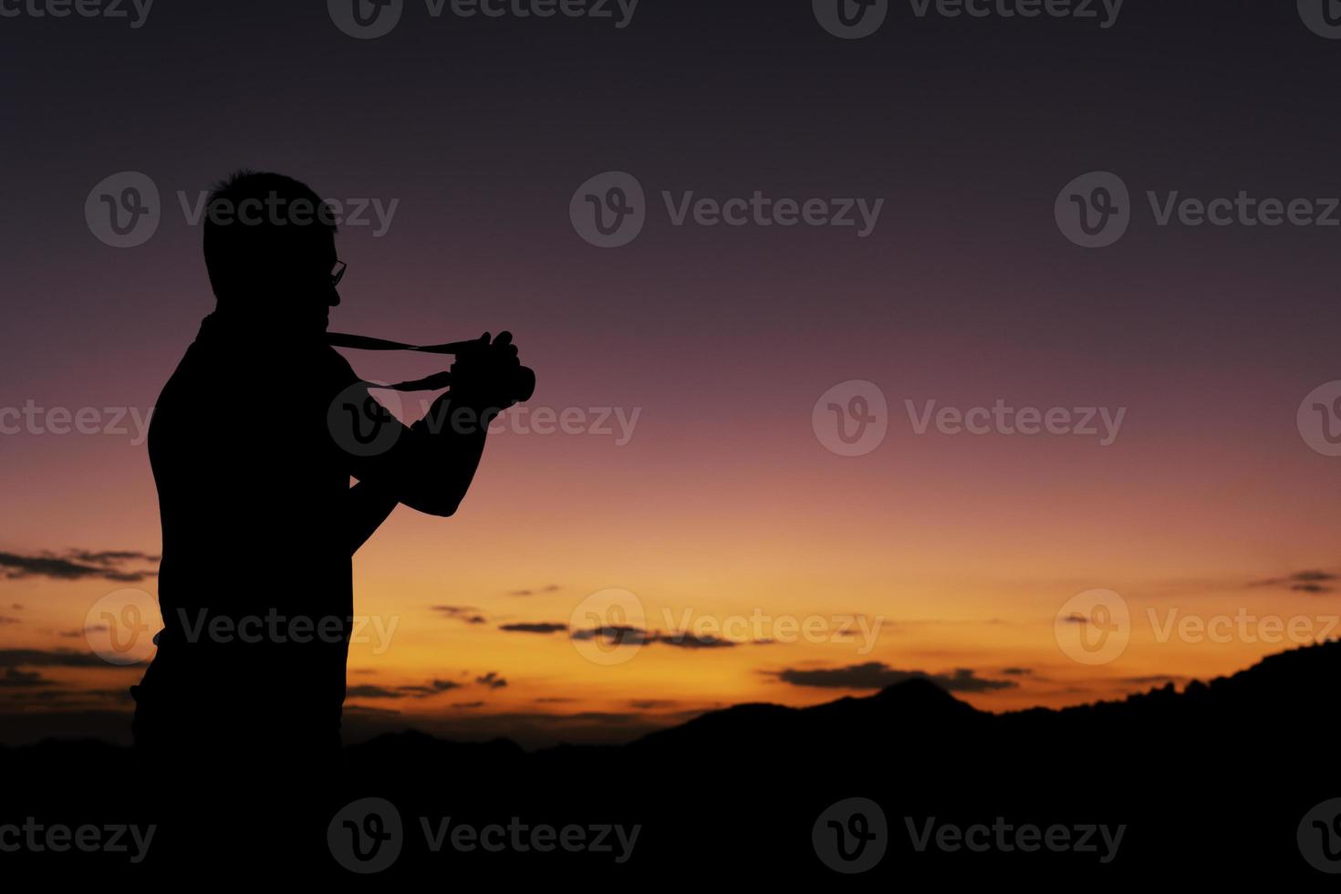 silueta de hombre tomando fotos del amanecer desde la montaña