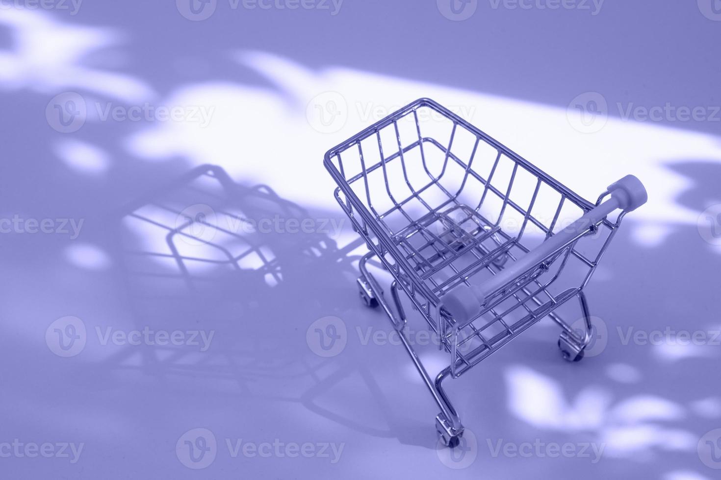 empty small shopping cart with nature hard shadows toned very peri coloe photo