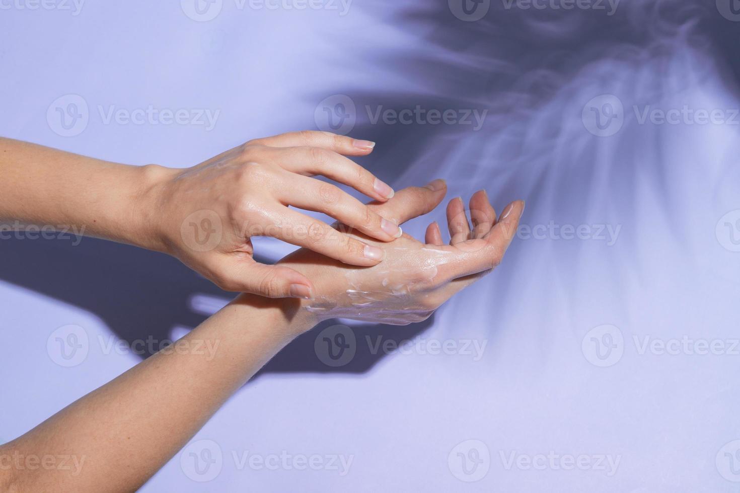 Hermosas manos femeninas en la luz del sol aplicar crema sobre fondo muy peri con sombra de hojas de palma foto