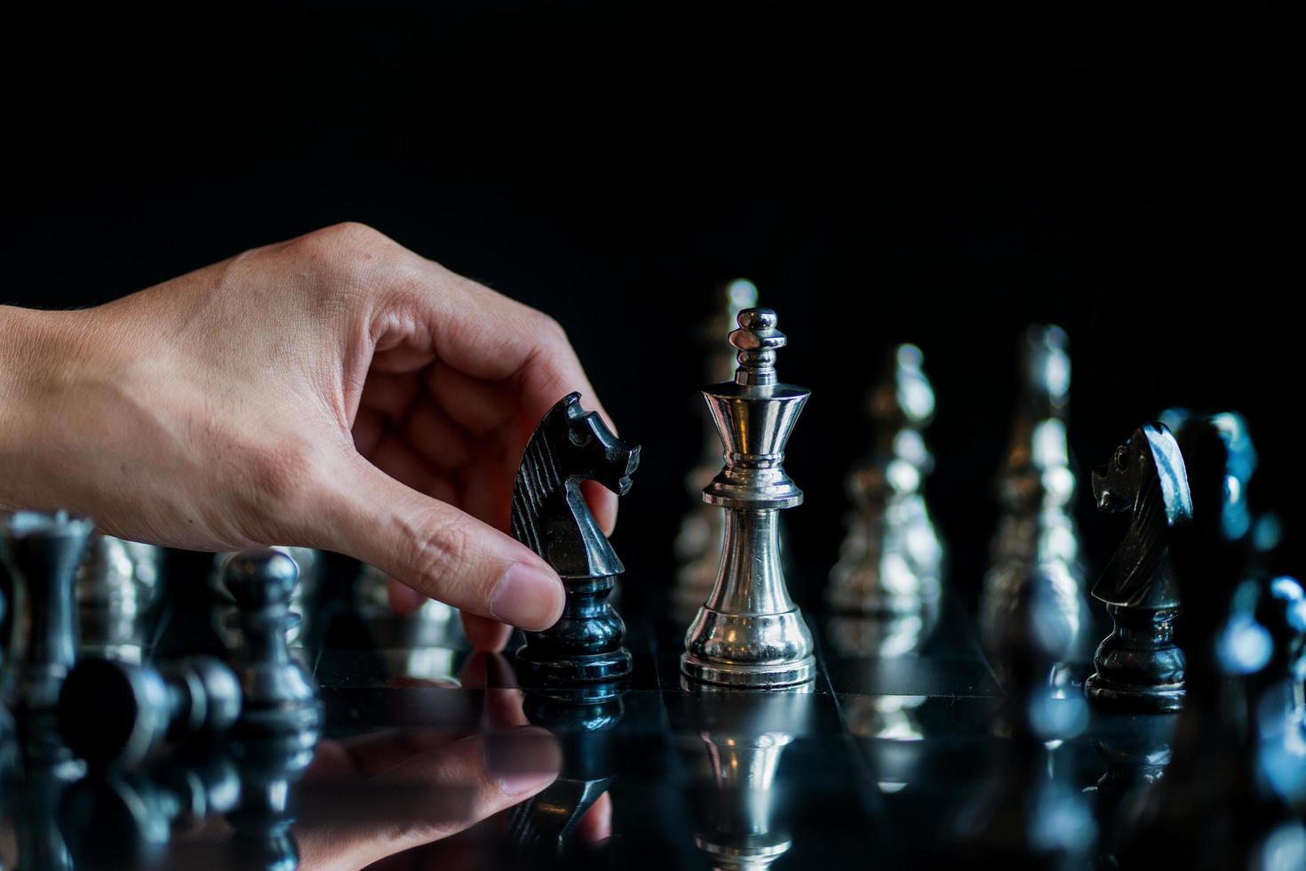 Mano del empresario moviendo el juego de tablero de ajedrez en el juego de éxito de la competencia foto