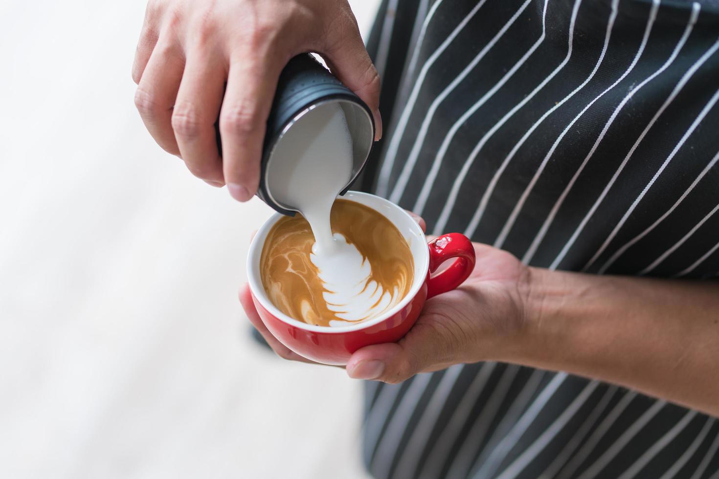 barista making latte or cappuccino coffee pouring milk photo