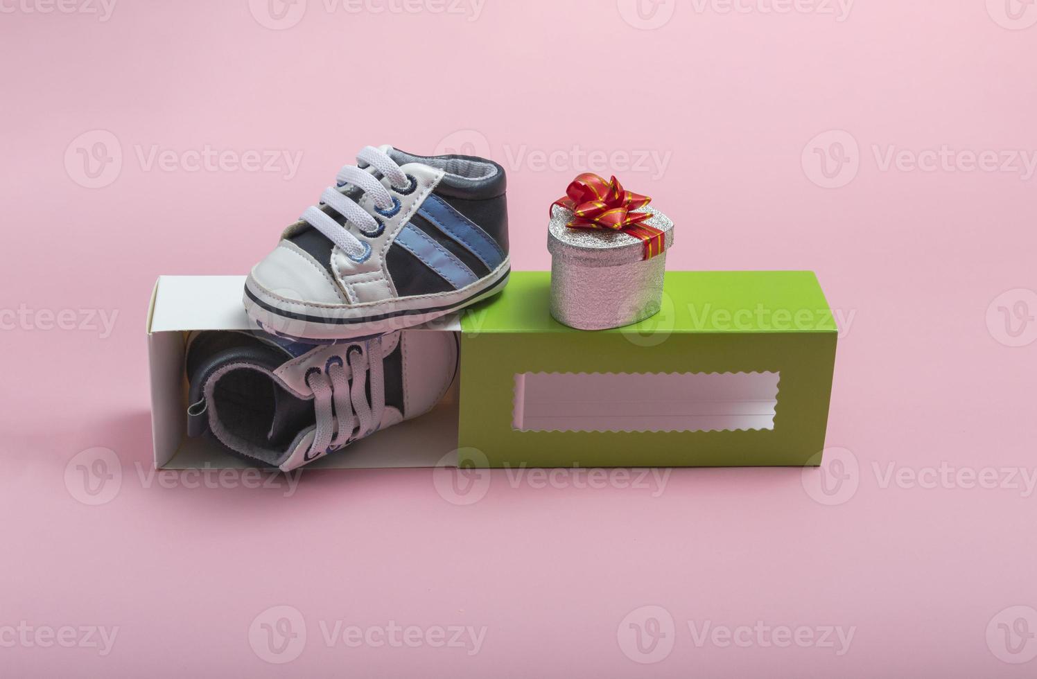 maqueta de zapatos para niños. Cerca de una caja de regalo y gumshoes para un recién nacido sobre un fondo de color. un regalo para el padre foto