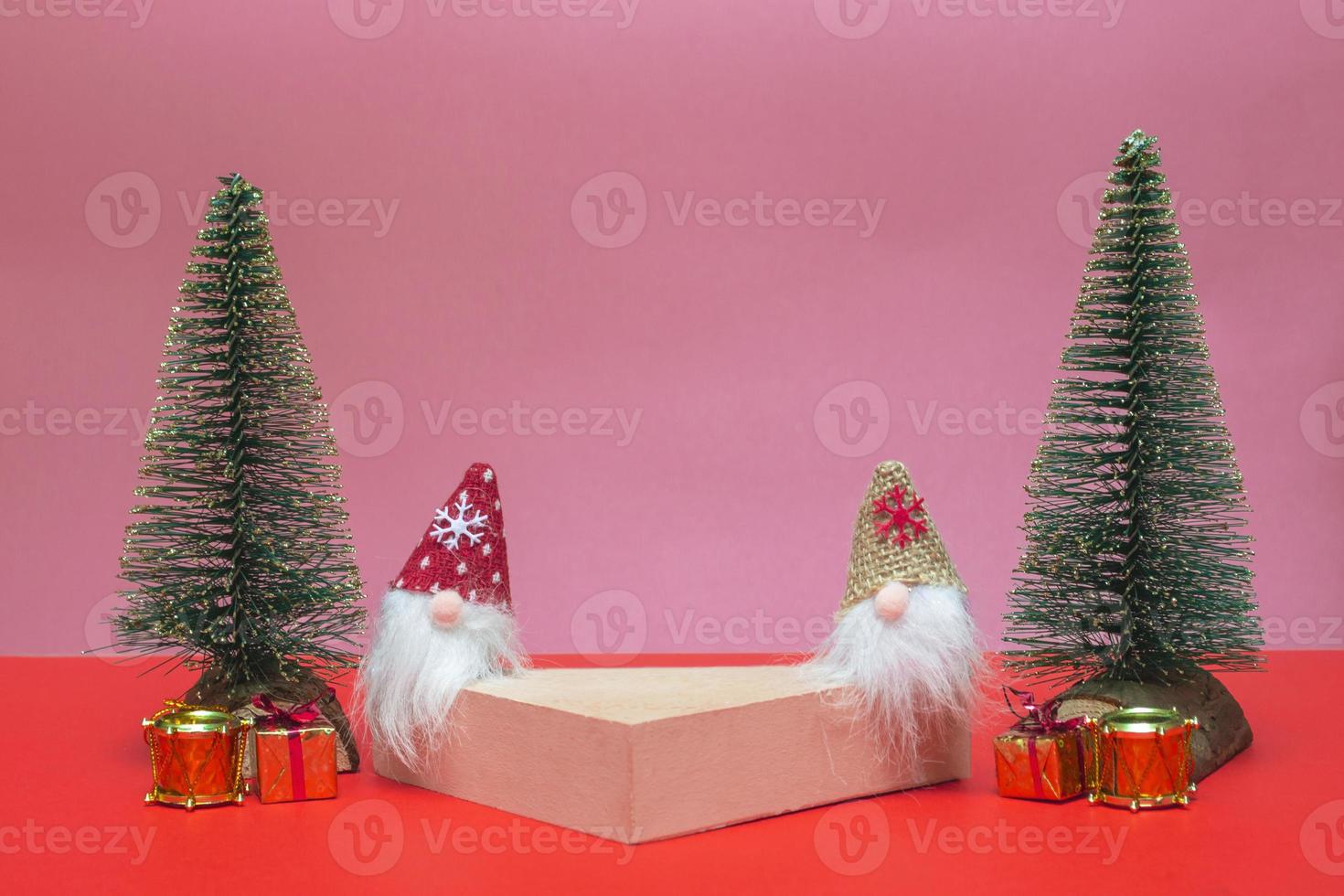 Festive concept. On a colored background, a podium for cosmetics and various goods with gnomes, gifts and Christmas trees. Close up with copy space photo