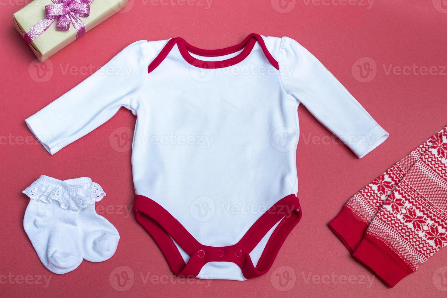 Christmas white baby bodysuit mockup on a colored background close up with red New Year's pants Mockup of clothes for newborns. With copy space photo