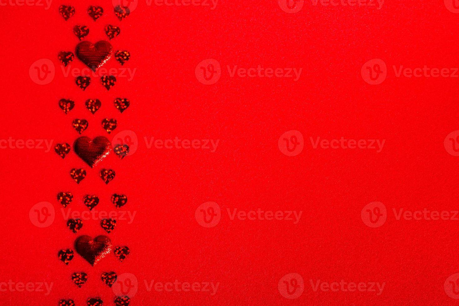 Red hearts of different sizes on a red textured background. Valentine's Day and Mother's Day festive banner copy space photo
