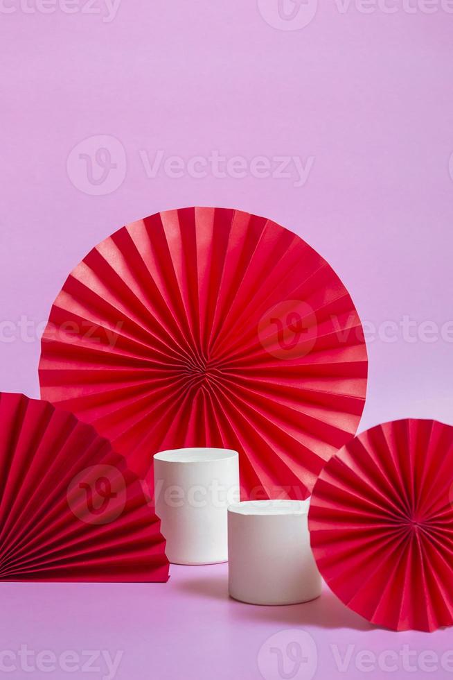 pantalla de podio blanca con fondo de abanico de arte de papel rojo para la presentación de la marca y el producto. formato vertical. de cerca foto