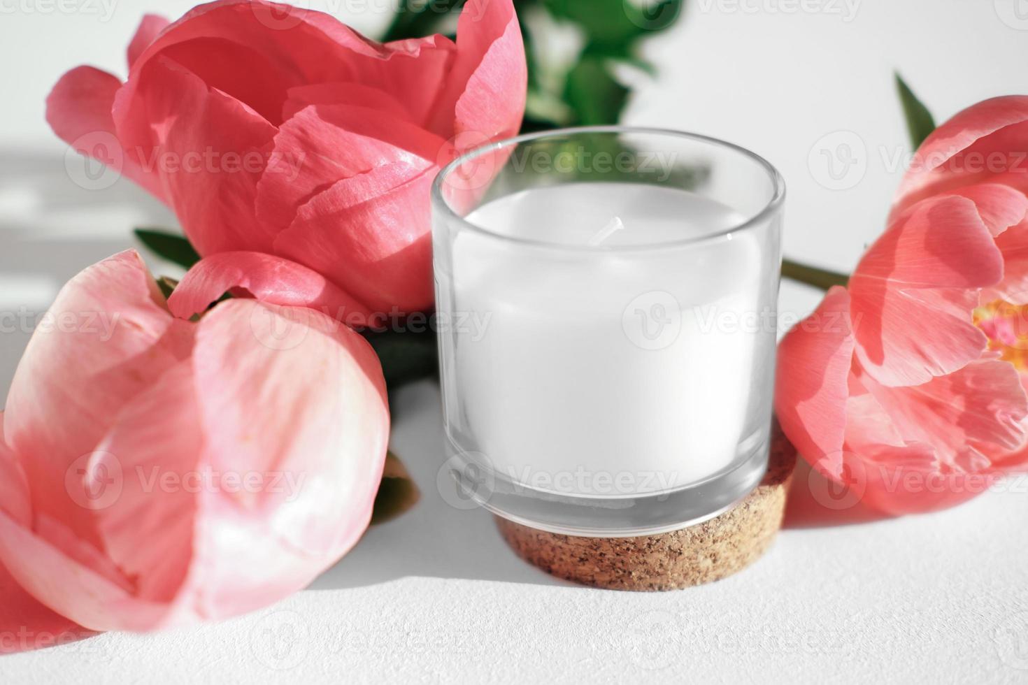 white scented candle and peony flowers. home fragrances for relaxation and calm. flower fragrance for home. unbranded ceramic candle photo