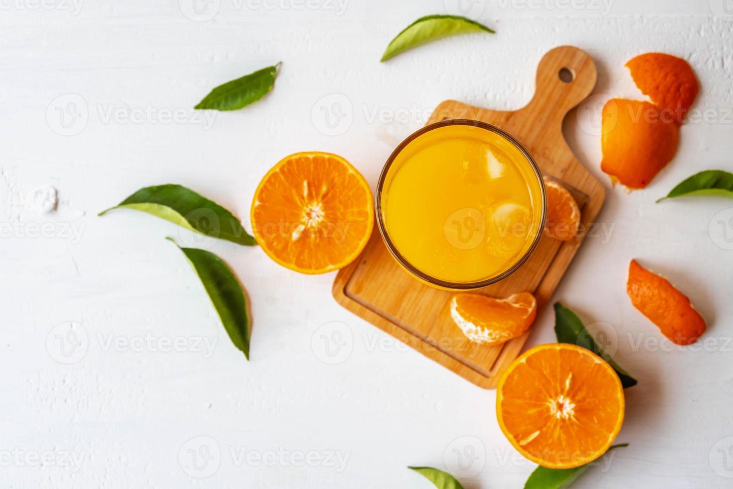 Jugo de naranja y frutas frescas de naranja sobre un fondo de madera blanca foto