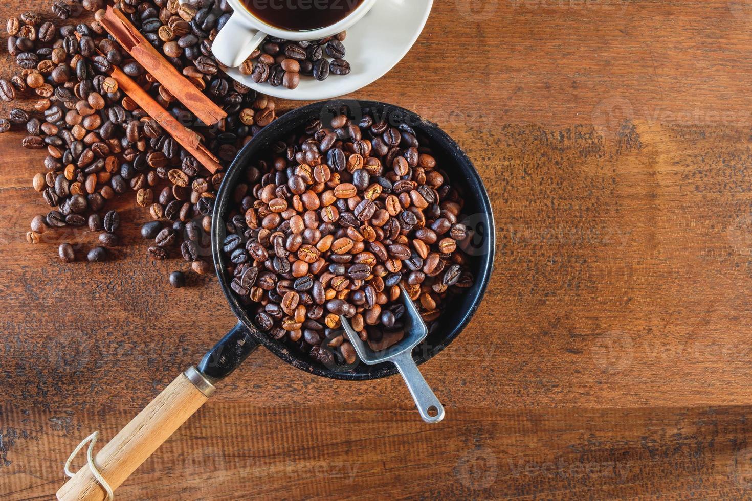 Top view of coffee beans roasted in a pan and a coffee cup. photo